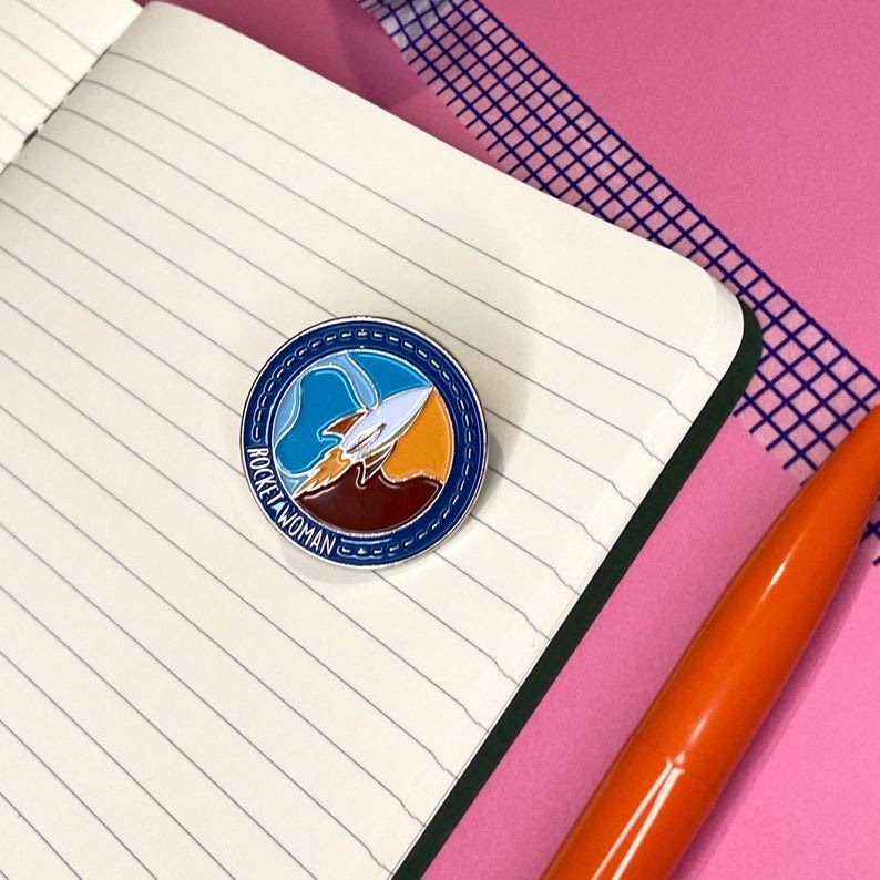 Rocket Woman pin design by Science On A Postcard, based on Rocket Women logo design by Marka Design